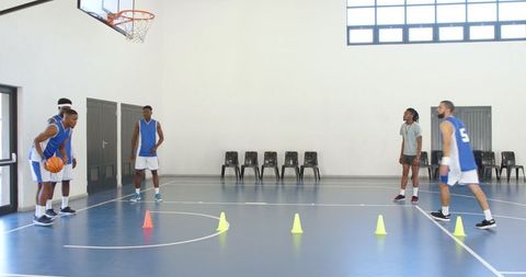 Team Practicing Basketball Drills with Cones in Indoor Gym