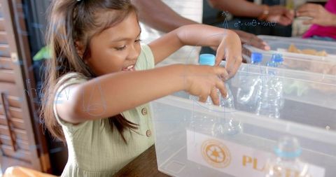 Young girl sorting plastic bottles into recycling bin teaching recycling and sustainability