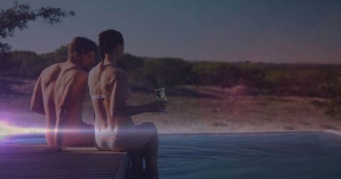 Couple Relaxing by Infinity Pool with Scenic Sunset View