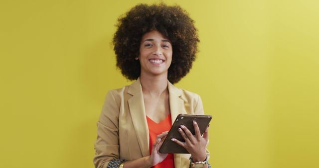 Image of happy biracial woman looking at camera on yellow background. business professionals and working in office concept.