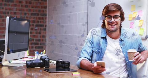 Young entrepreneur holding smartphone in creative office environment