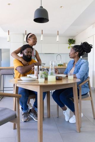 African american family sharing breakfast at round wooden table in modern kitchen together