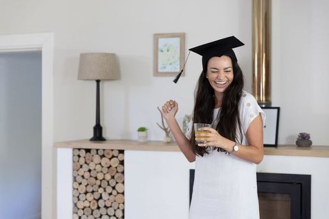 Woman celebrating graduation with mortarboard indoors