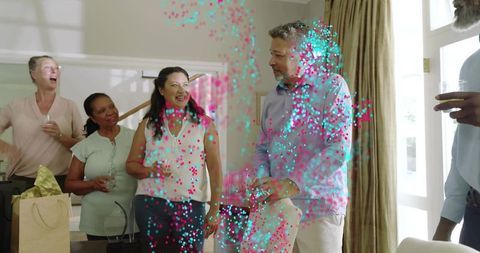 Multigenerational friends celebrating at home laughing and toasting with confetti