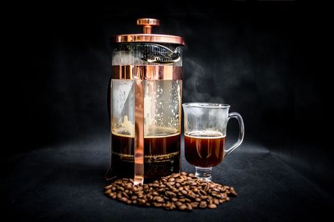 French press coffee alongside glass mug and coffee beans