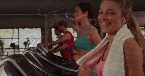 Woman running on treadmill with towel and earbuds in gym