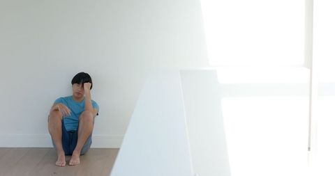 Asian Young Adult Sitting Pensive on Floor in Minimalist Space - Download Free Stock Images Pikwizard.com