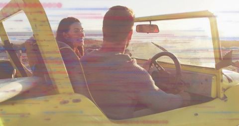 Sunset coastal road trip with couple driving yellow convertible at golden hour, smiling