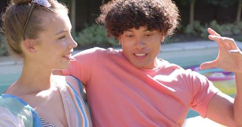 Friends Sitting by Pool Chatting and Enjoying Sunny Day