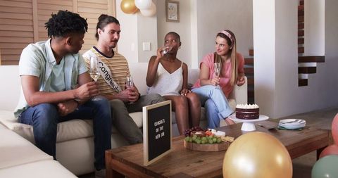Friends Having Celebratory Gathering at Home with Snacks and Beverages
