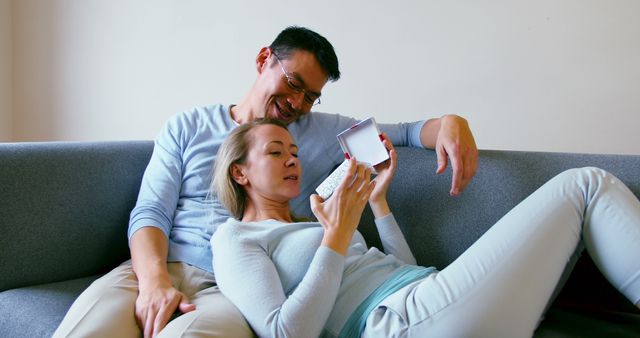 Man giving a surprise gift to her woman in living room at home - Download Free Stock Photos Pikwizard.com