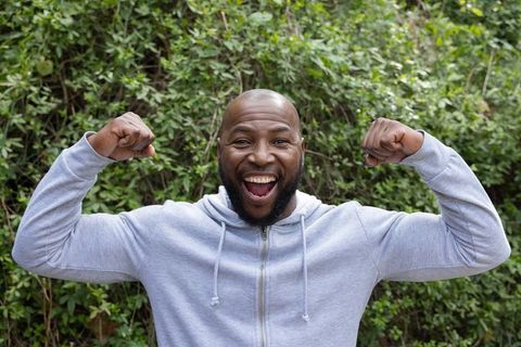 African american man celebrating victory smiling and flexing muscles outdoors