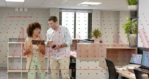 Young professionals collaborating over tablet with financial data overlay in modern office