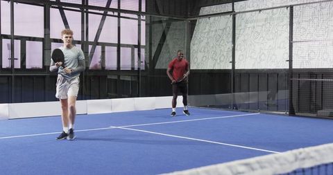 Energetic Male Athletes Playing Padel on Blue Court