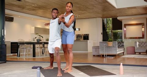 African american couple practicing yoga at home with guidance