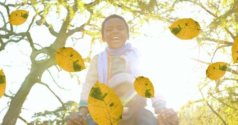 Joyful Father and Son under Falling Autumn Leaves in Park