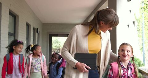 Teacher Leading School Children Along Bright Corridor