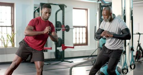 African american personal trainer coaching client performing lateral lunges in modern gym
