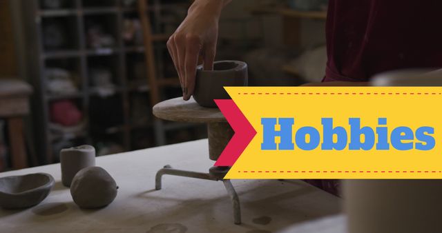 Hand shaping a ceramic pot on a pottery wheel in a hobbies workshop. Suitable for illustrating art and craft activities, hobby classes, and artistic expressions. Ideal for websites, blogs, magazines about crafts, pottery, DIY projects, and creative hobbies.