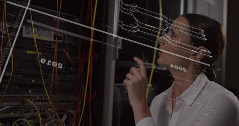 Female engineer analyzing network cables in server room