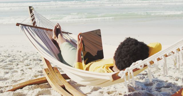 African american woman with tablet lying in hammock on sunny beach - Download Free Stock Photos Pikwizard.com