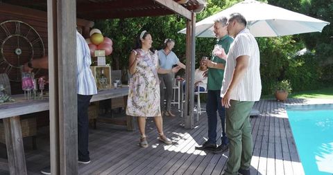 Senior friends socializing poolside at summer garden party