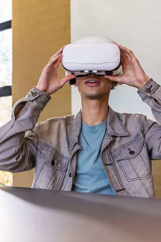 Male Adjusting White VR Headset Wearing Denim Jacket Immersive Virtual Reality Experience