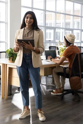 Young professional woman presenting tablet in bright open-plan office coworking space