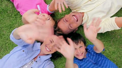 Joyful Family Relaxing on Green Grass in Park
