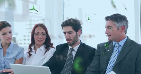 Collaborating business team reviewing sustainable energy data on laptop in modern office