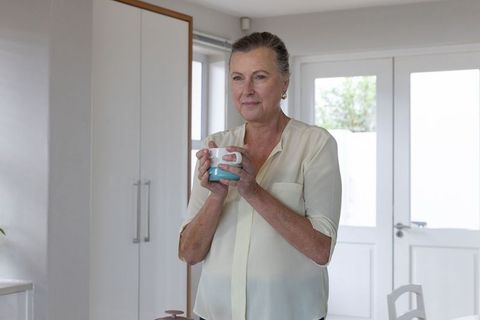 Senior Woman Enjoying Morning Coffee in Bright Minimalist Kitchen