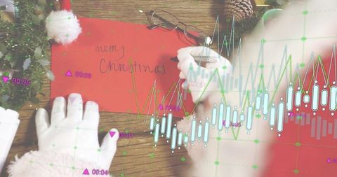 Santa-sleeved hands writing Merry Christmas on red envelope with financial chart overlay