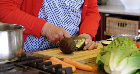 Senior Woman Chopping Fresh Avocado in Kitchen