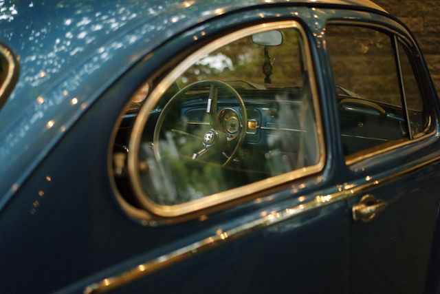This image shows a close-up of a vintage blue car's interior with focus on the steering wheel and dashboard. Ideal for use in automotive-related content, vintage car promotions, or retro-themed projects. Works well for illustrating nostalgia, classic car events, and historical automotive designs.