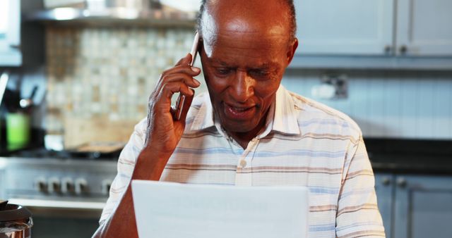 Senior Man Talking on Phone While Reading Document in Modern Kitchen - Download Free Stock Images Pikwizard.com