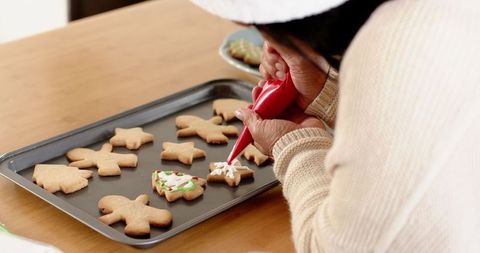 Senior woman decorating festive gingerbread cookies at home