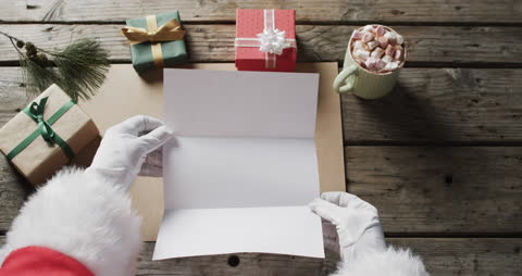 Santa Reviewing Christmas Letters with Gift Boxes and Cocoa