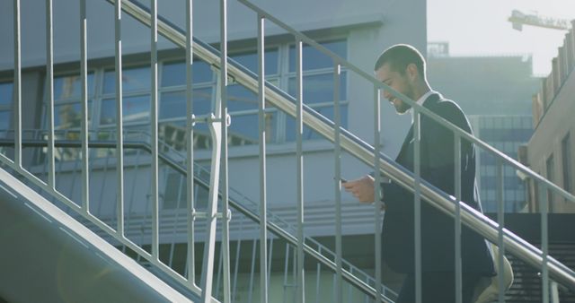 Businessman Walking Down Stairs Checking Smartphone in Urban Area - Download Free Stock Images Pikwizard.com