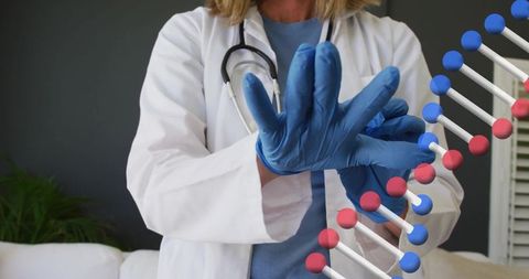 Female clinician donning blue gloves with dna double-helix overlay
