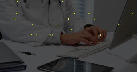 Doctor Typing on Computer in Medical Office with Work Essentials