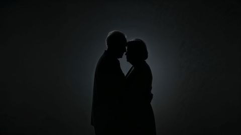 Silhouette of romantic old people touching foreheads with halo glow
