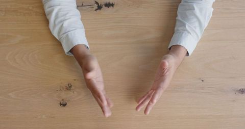 Businessman gesturing with open hands at wooden desk