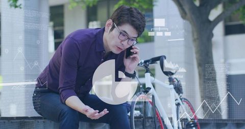 Mature asian professional talking on smartphone by bicycle with business data overlays