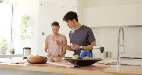 Sunlit modern kitchen couple preparing healthy breakfast at wooden island, bright lifestyle