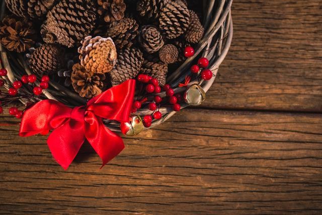 Grapevine wreath with red ribbon and pine cone on wooden table