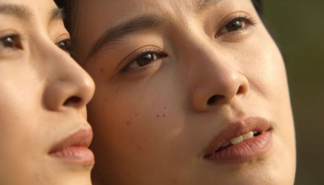 Sunlit close-up of two asian women gazing during golden hour, intimate beauty portrait
