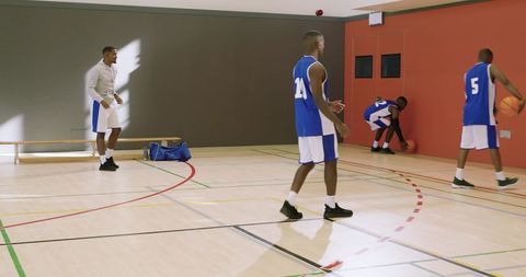 Basketball team practicing drill player 24 walking near three-point arc on indoor court
