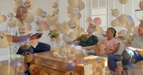 Multigenerational family sharing tablet with floating emoji overlay in sunlit living room