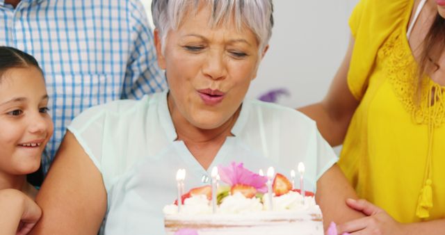 Elderly Woman Blowing Out Candles on Birthday Cake with Family - Download Free Stock Images Pikwizard.com