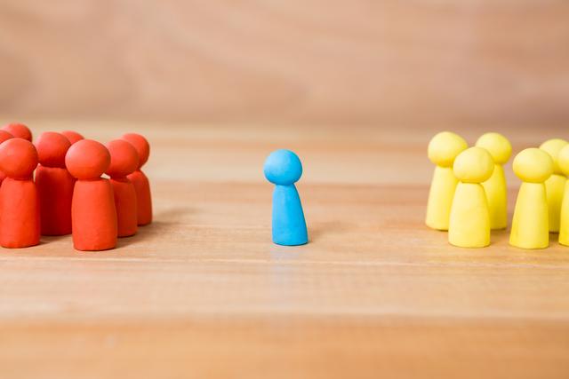 Conceptual image of blue figurine standing between a group of red and yellow figurines